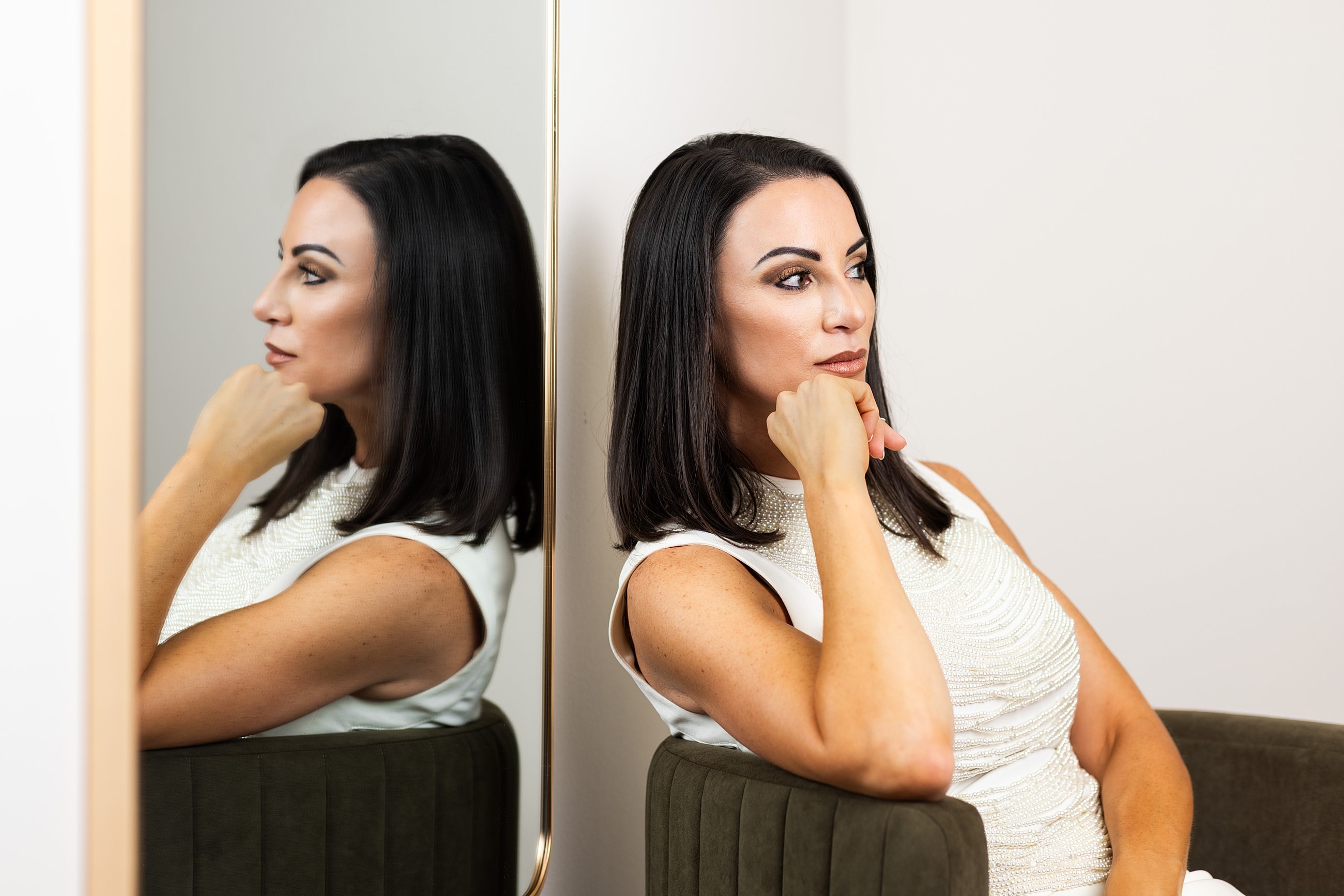 Woman thoughtfully posing next to a mirror.