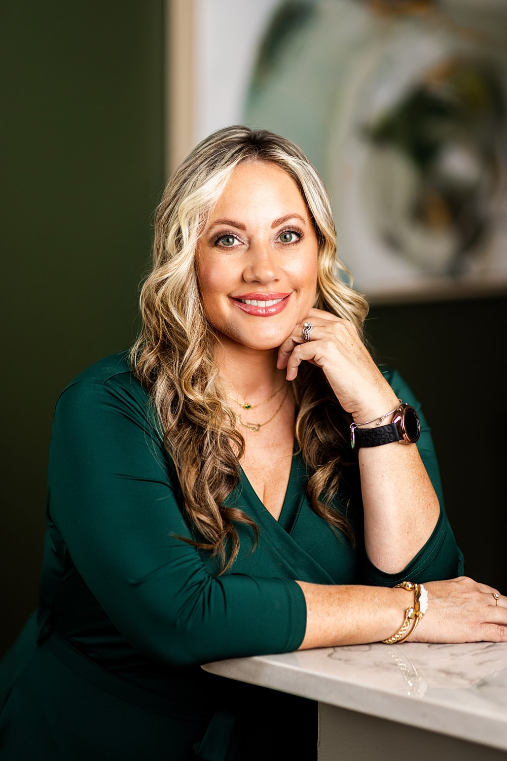 Smiling woman in green dress at countertop.