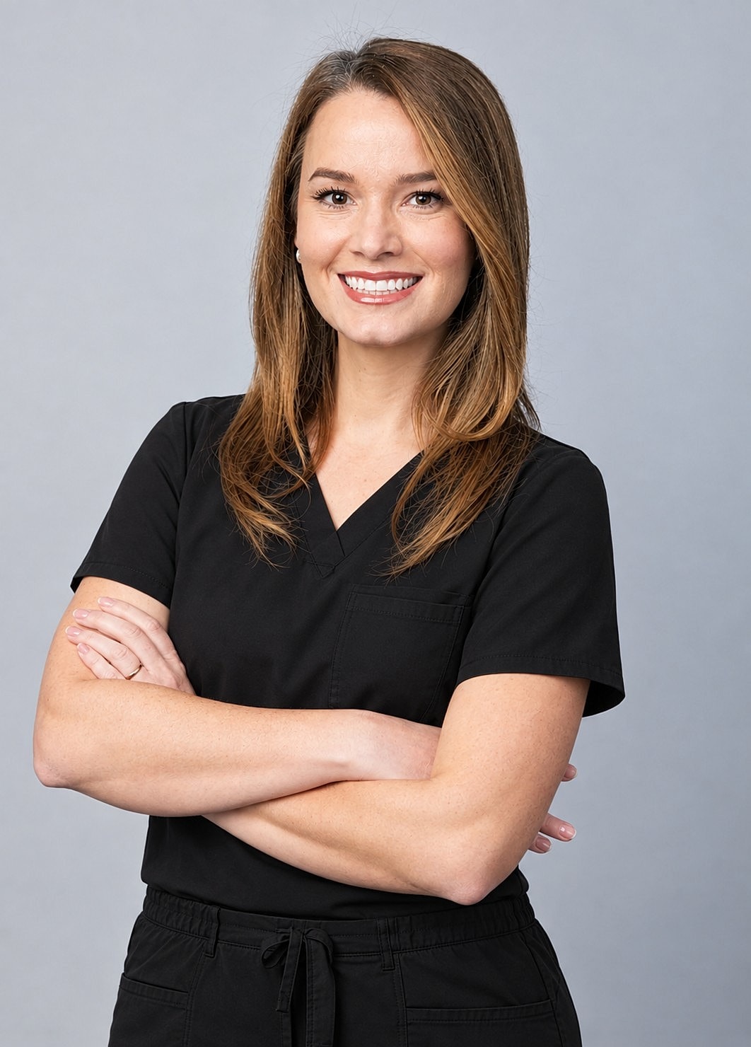 Smiling woman in black scrubs with crossed arms.