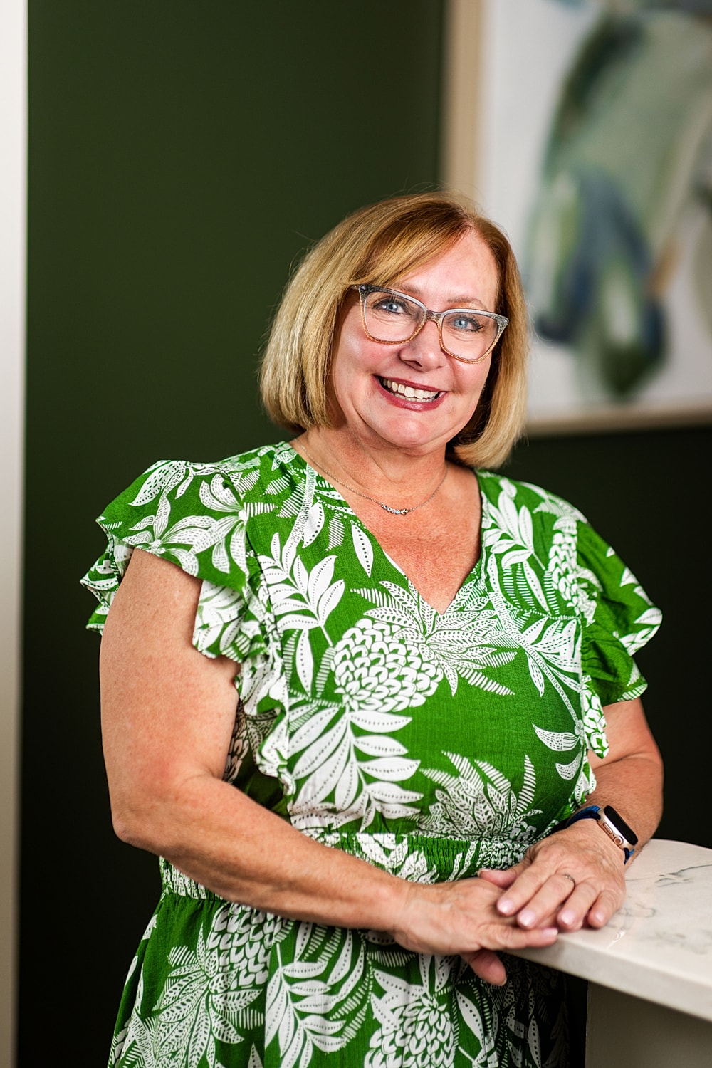 Smiling woman in green floral dress.